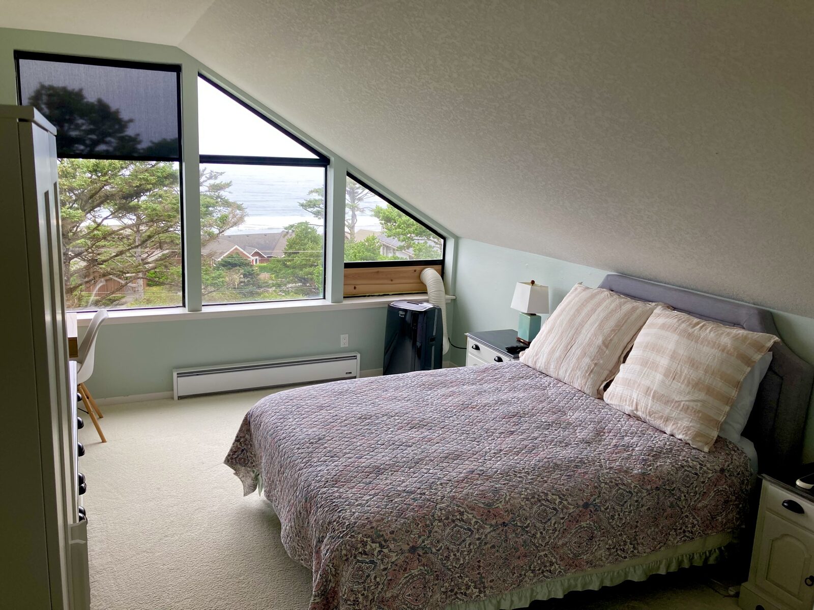 Bright ocean-view bedroom with freshly made bed and vacuumed carpet