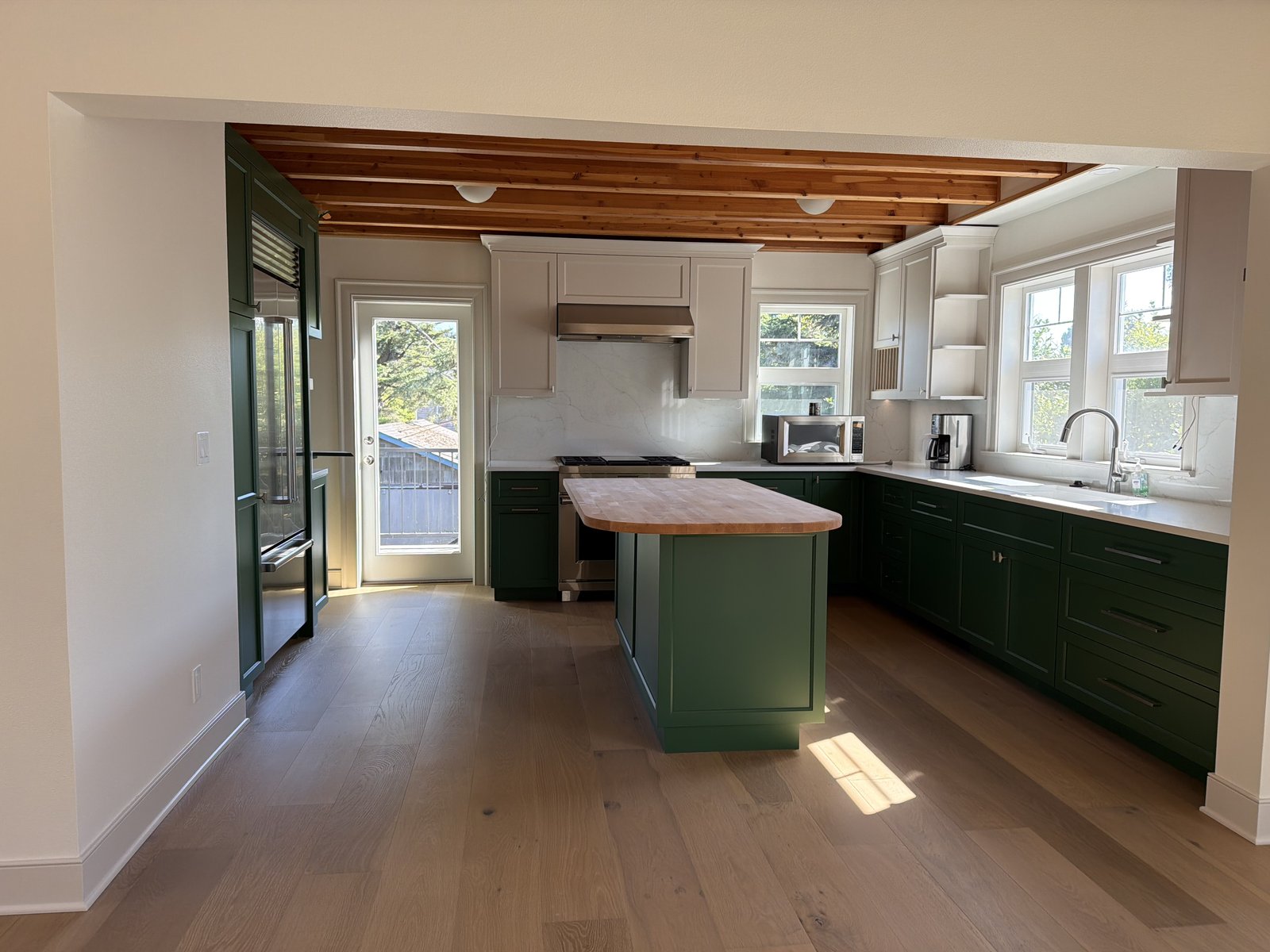 Clean kitchen with green island and polished wood floors