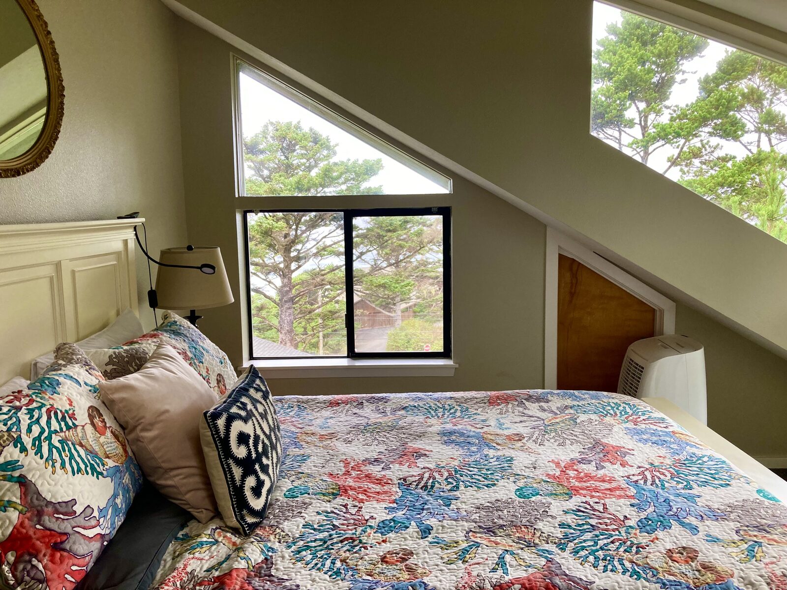 Guest bedroom made up with fresh linens and a view of coastal pines