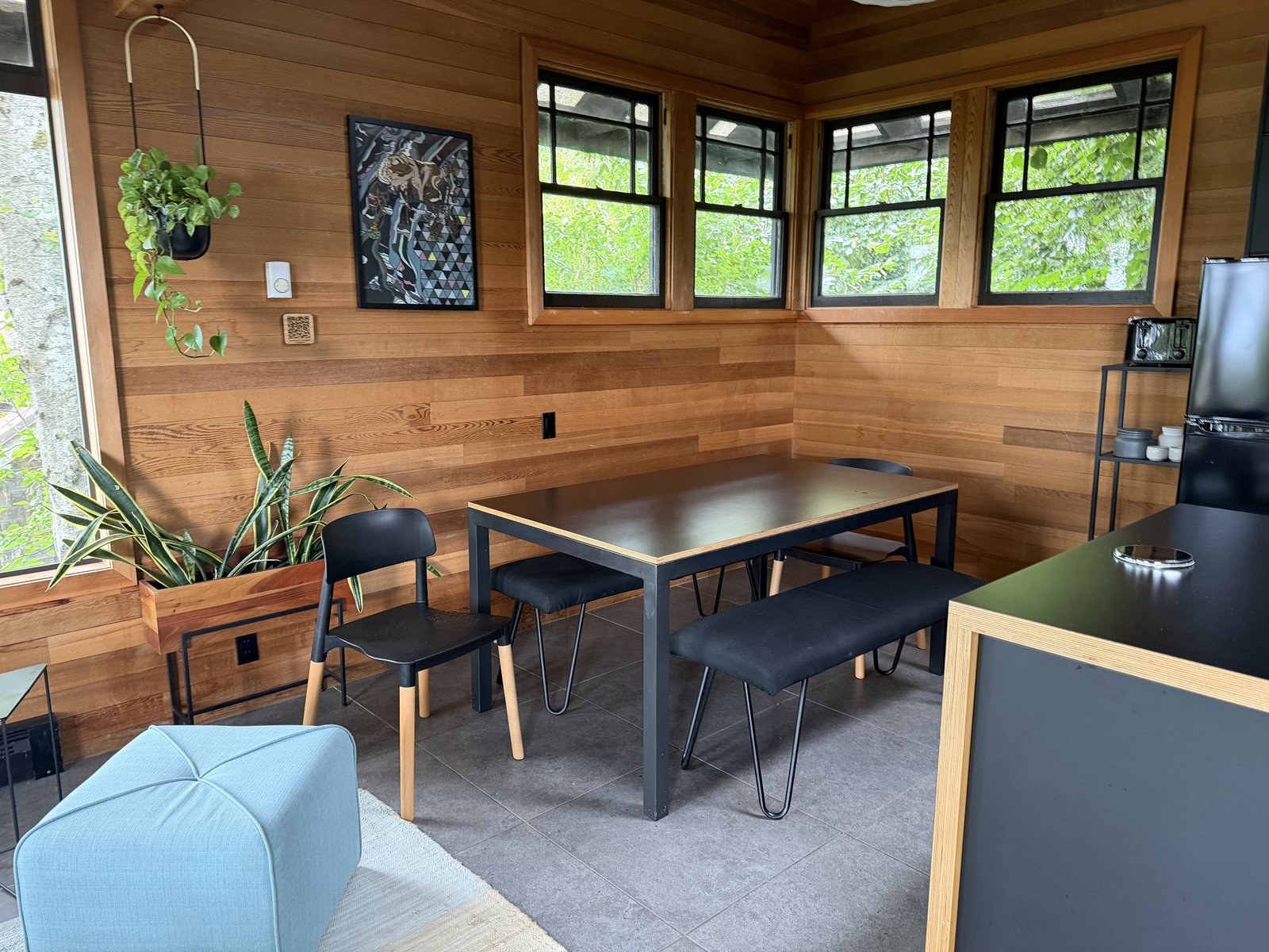 Dining and living space with wood walls and large windows